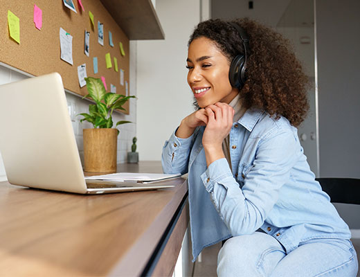 Student in the Columbia Online MSSW Two-Year program wearing headphones and looking at laptop