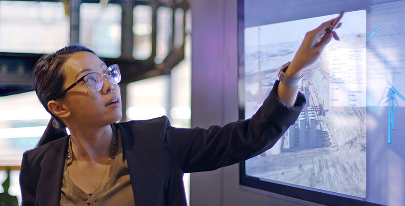 A woman pointing to an office display screen