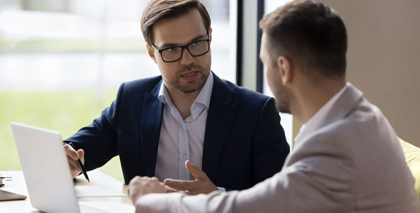 Two men talking at a laptop